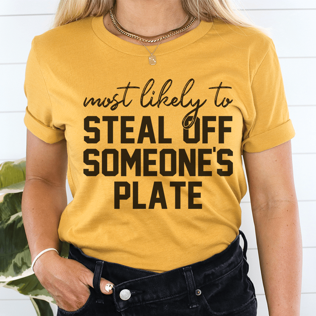 A comfortable Thanksgiving t-shirt featuring the phrase 'Most Likely To Steal Off Someone's Plate', made from soft cotton.