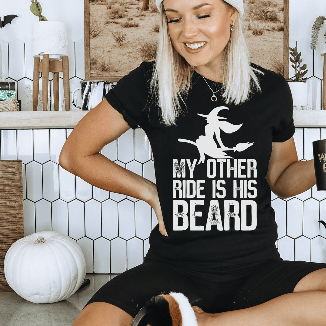 A humorous t-shirt featuring the phrase 'My Other Ride Is His Beard', made from soft cotton with double stitching for durability.