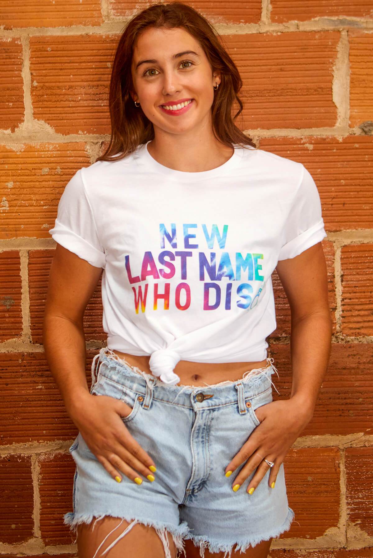 A vibrant white shirt featuring the phrase 'New Last Name Who Dis' in a colorful tie-dye print, perfect for brides.