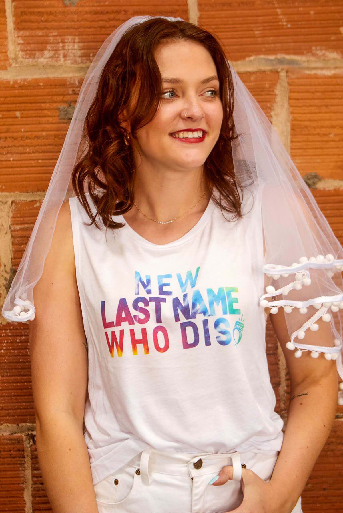 A vibrant white shirt featuring the phrase 'New Last Name Who Dis' in a colorful tie-dye print, perfect for brides.