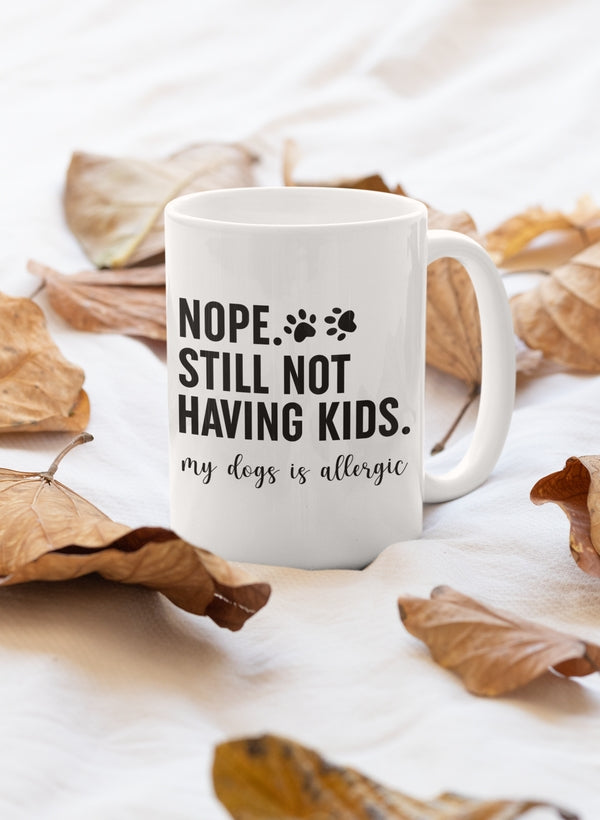 A glossy white ceramic mug with the phrase 'Nope Still Not Having Kids' printed in bold letters, showcasing a sturdy handle.