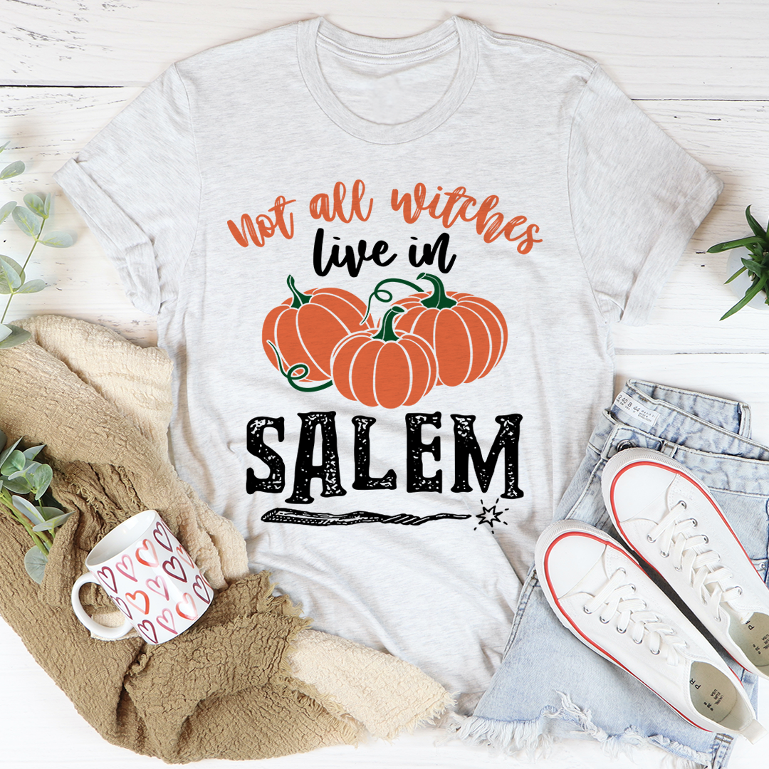 A stylish black t-shirt featuring the phrase 'Not All Witches Live In Salem' in a whimsical font, made from soft ring-spun cotton.