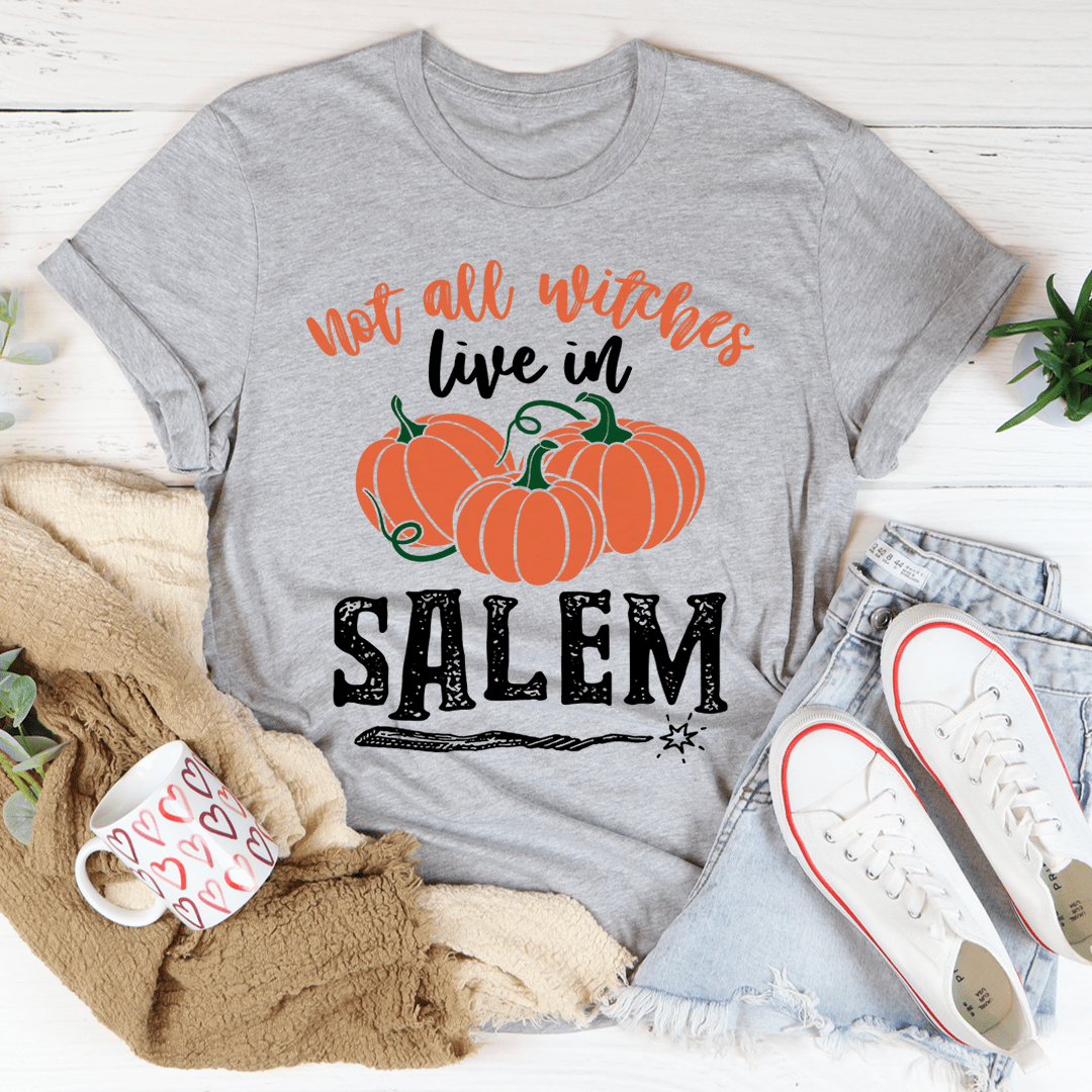 A stylish black t-shirt featuring the phrase 'Not All Witches Live In Salem' in a whimsical font, made from soft ring-spun cotton.