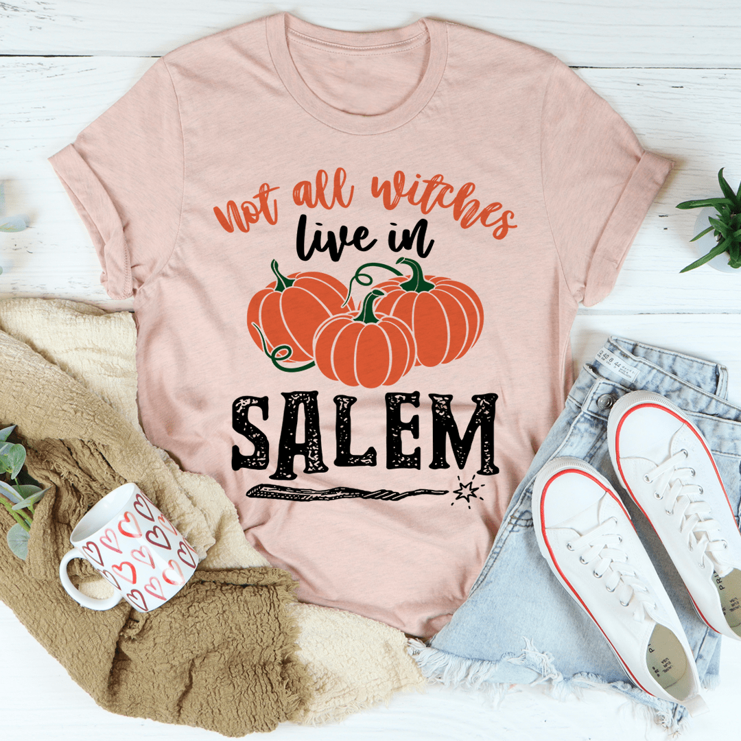 A stylish black t-shirt featuring the phrase 'Not All Witches Live In Salem' in a whimsical font, made from soft ring-spun cotton.