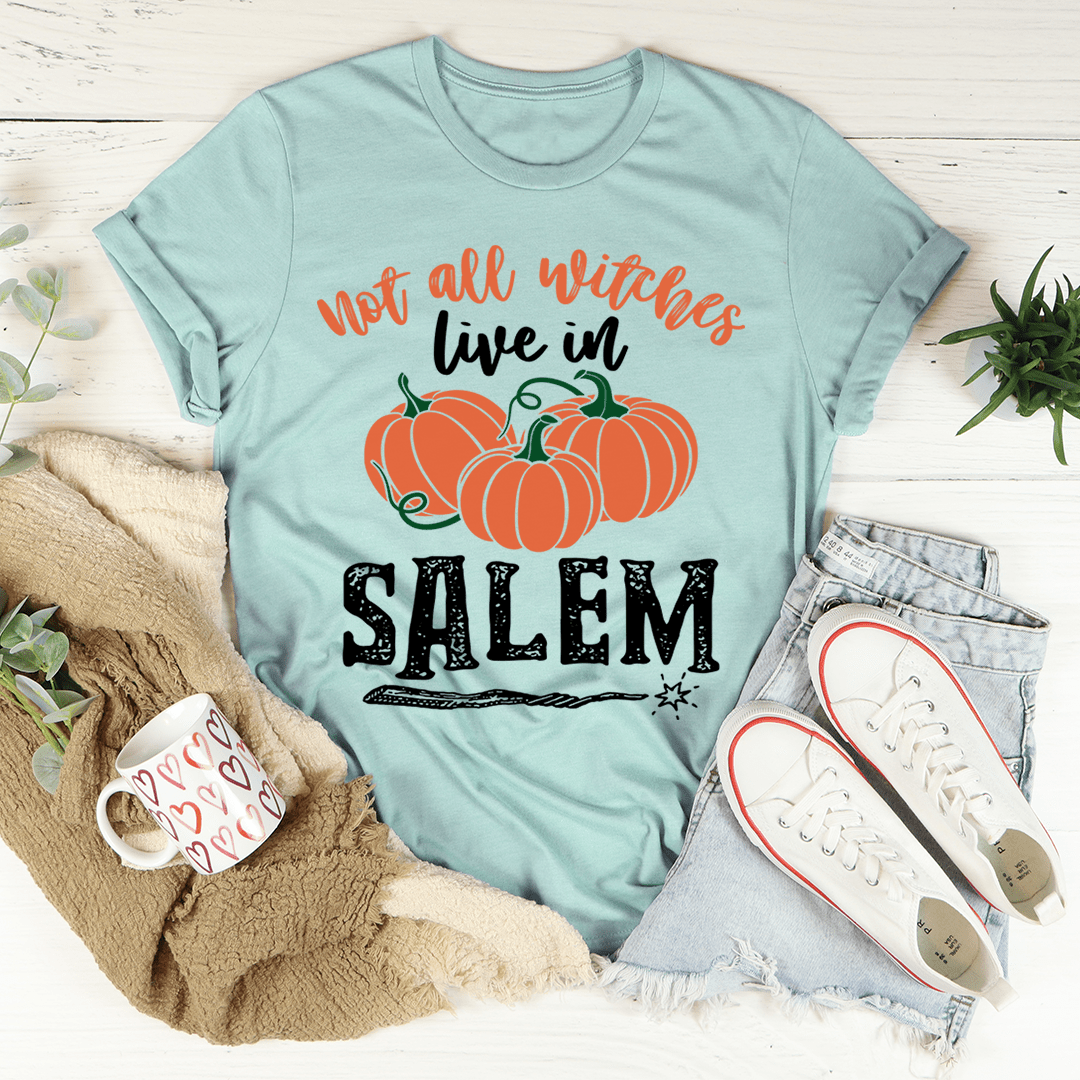 A stylish black t-shirt featuring the phrase 'Not All Witches Live In Salem' in a whimsical font, made from soft ring-spun cotton.