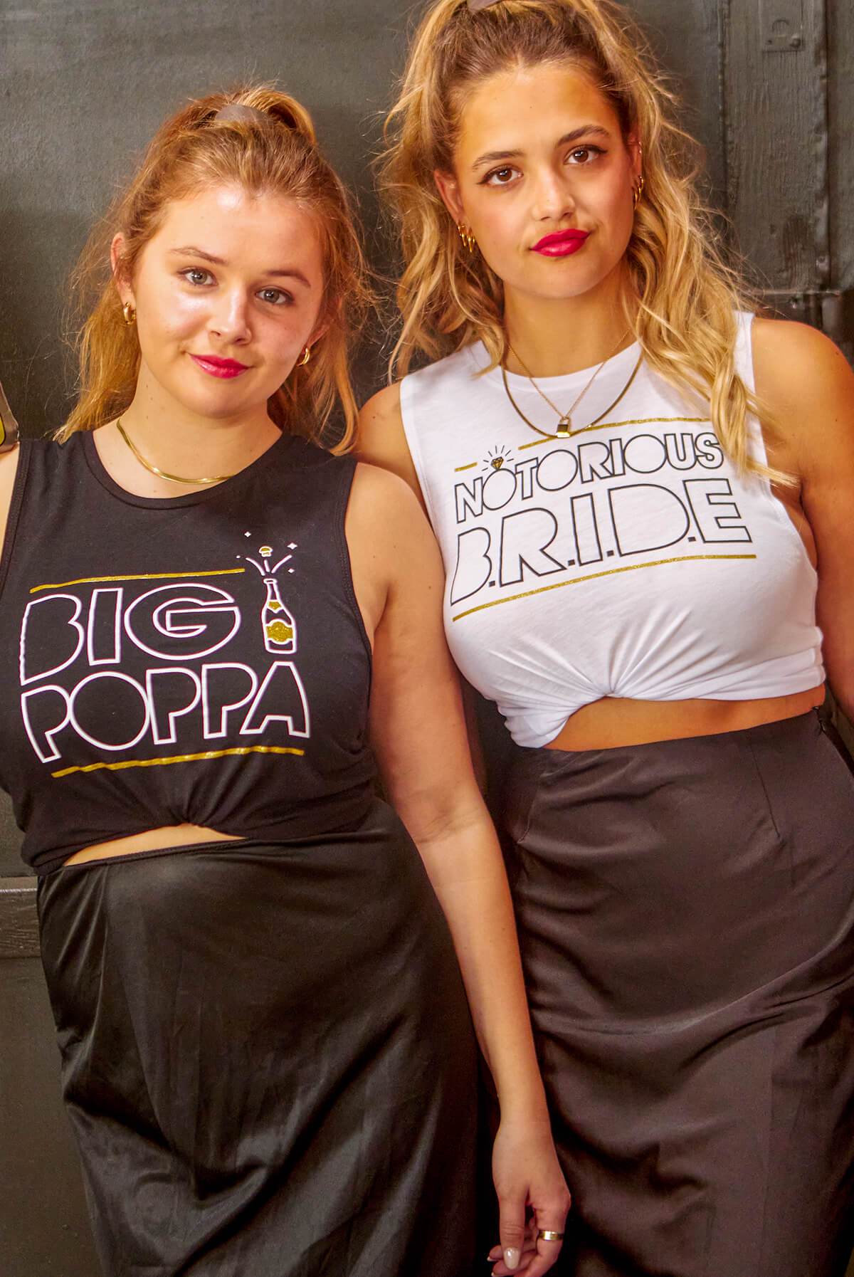 White and black muscle tank tops with 'Notorious Bride' and 'Big Poppa' printed designs, perfect for a bachelorette party.