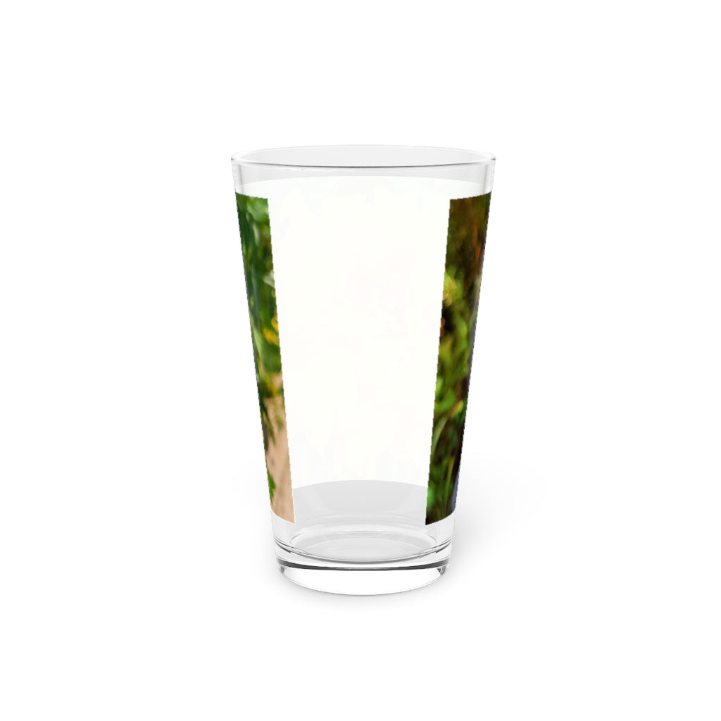 A clear 16oz pint glass featuring an elegant orange flower design, perfect for beverages.