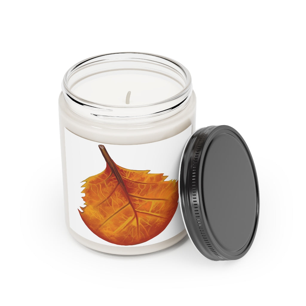 A hand-poured Orange Leaf Scented Candle in a glass container, showcasing its vibrant color and elegant design.