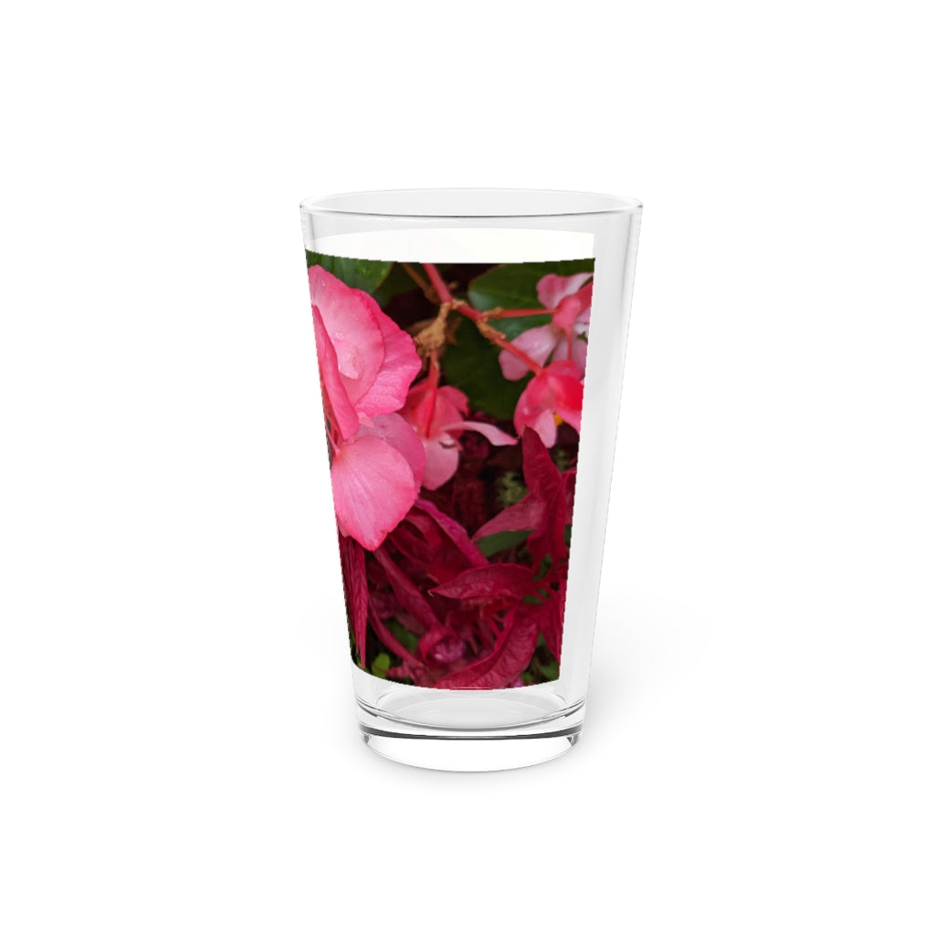 A clear 16oz pint glass featuring a pink flower design, perfect for personalized beverages.