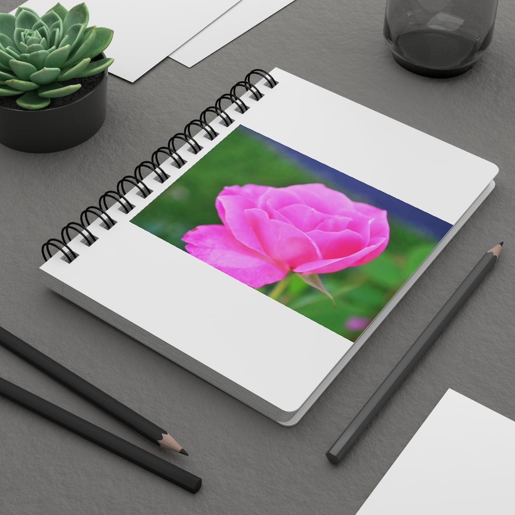 A stylish pink flower spiral bound journal with a glossy laminated cover, featuring vibrant floral designs and lined pages.