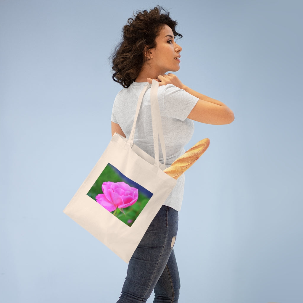 A stylish pink flower tote bag made of 100% cotton with long handles and cross stitching for added durability.