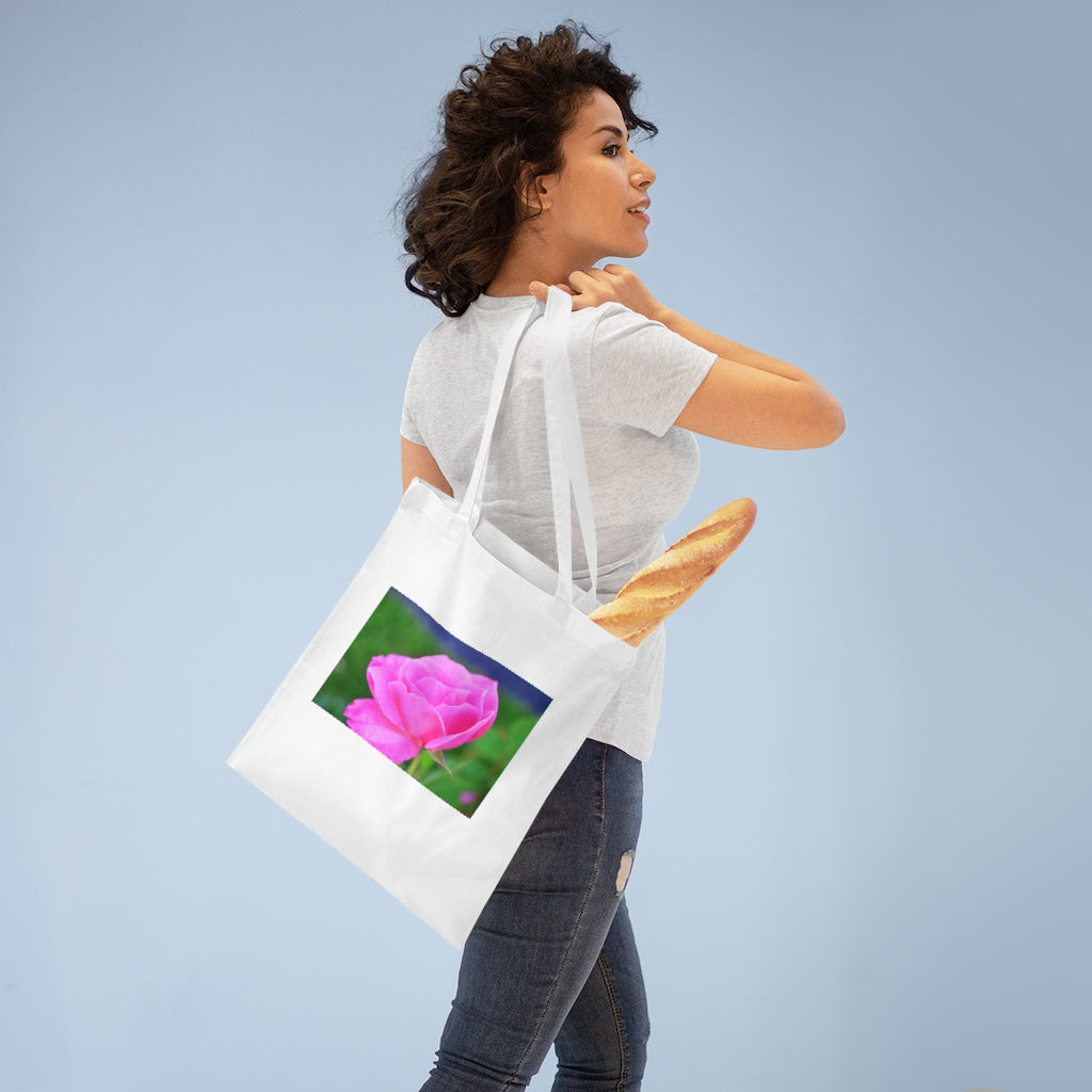 A stylish pink flower tote bag made of 100% cotton with long handles and cross stitching for added durability.