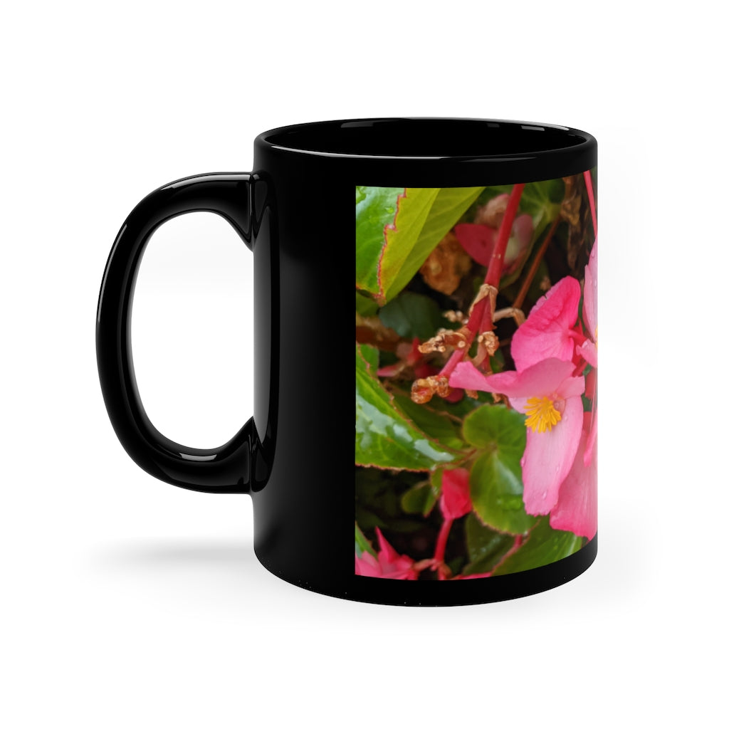 A stylish black ceramic mug featuring vibrant pink flowers, perfect for coffee, tea, or hot chocolate.