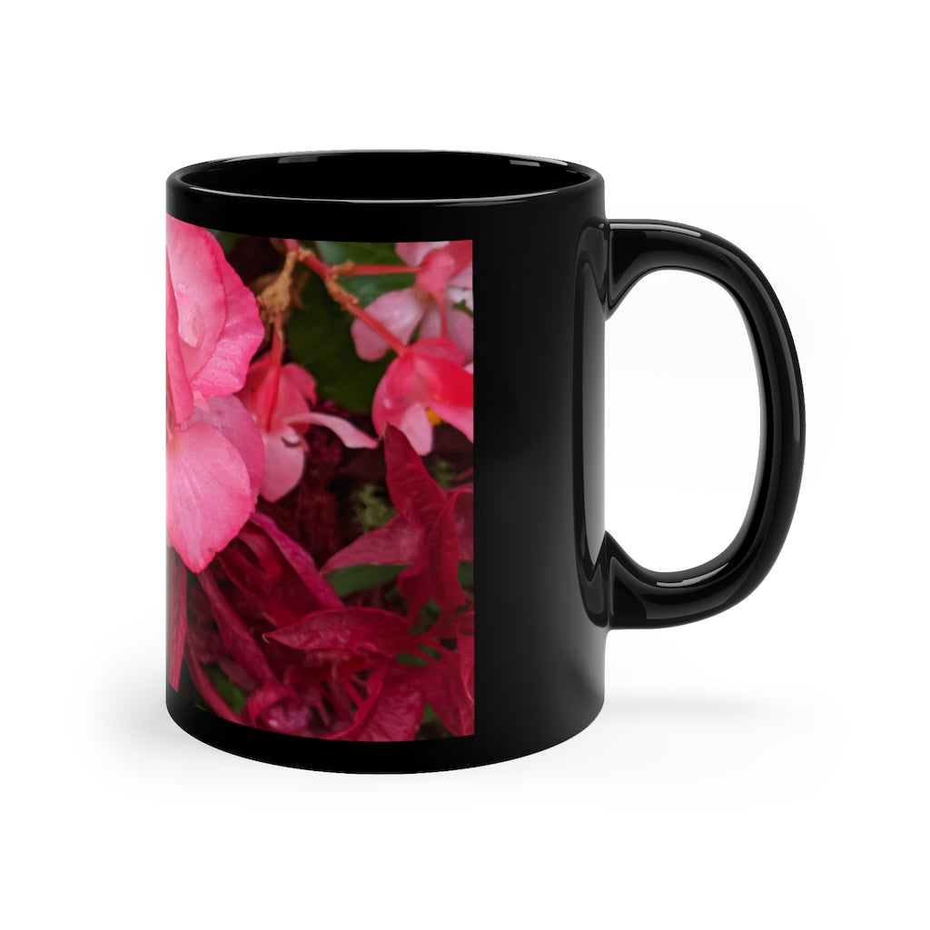 A stylish black ceramic mug featuring vibrant pink flowers, perfect for coffee, tea, or hot chocolate.