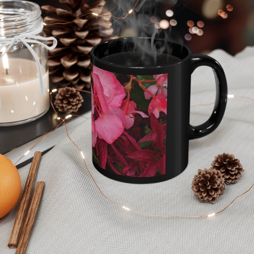 A stylish black ceramic mug featuring vibrant pink flowers, perfect for coffee, tea, or hot chocolate.