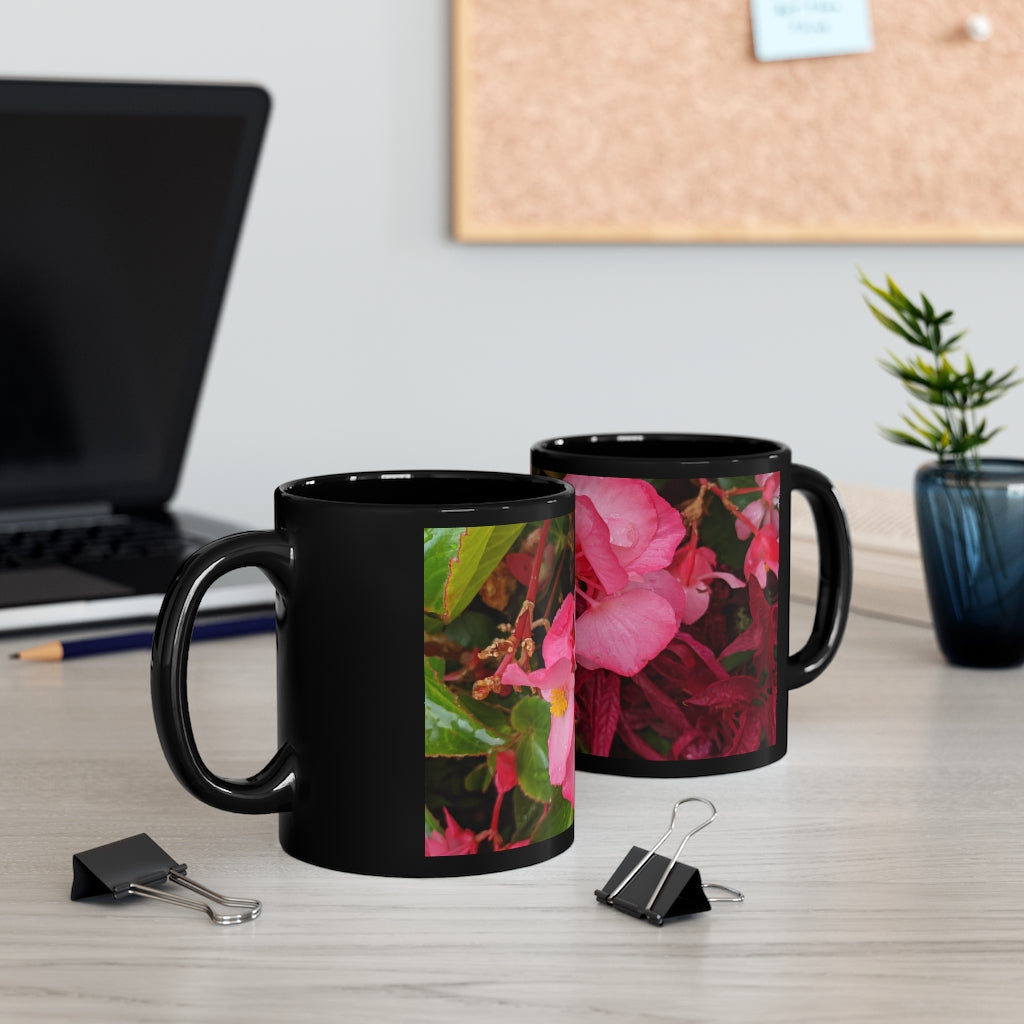 A stylish black ceramic mug featuring vibrant pink flowers, perfect for coffee, tea, or hot chocolate.