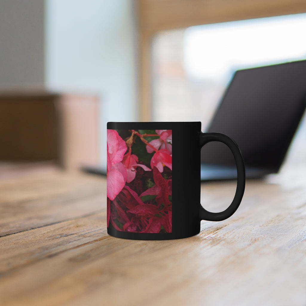 A stylish black ceramic mug featuring vibrant pink flowers, perfect for coffee, tea, or hot chocolate.