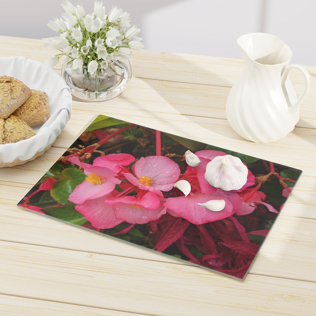 A stylish Pink Flowers Cutting Board made of tempered glass with a floral design and rubber dots for stability.