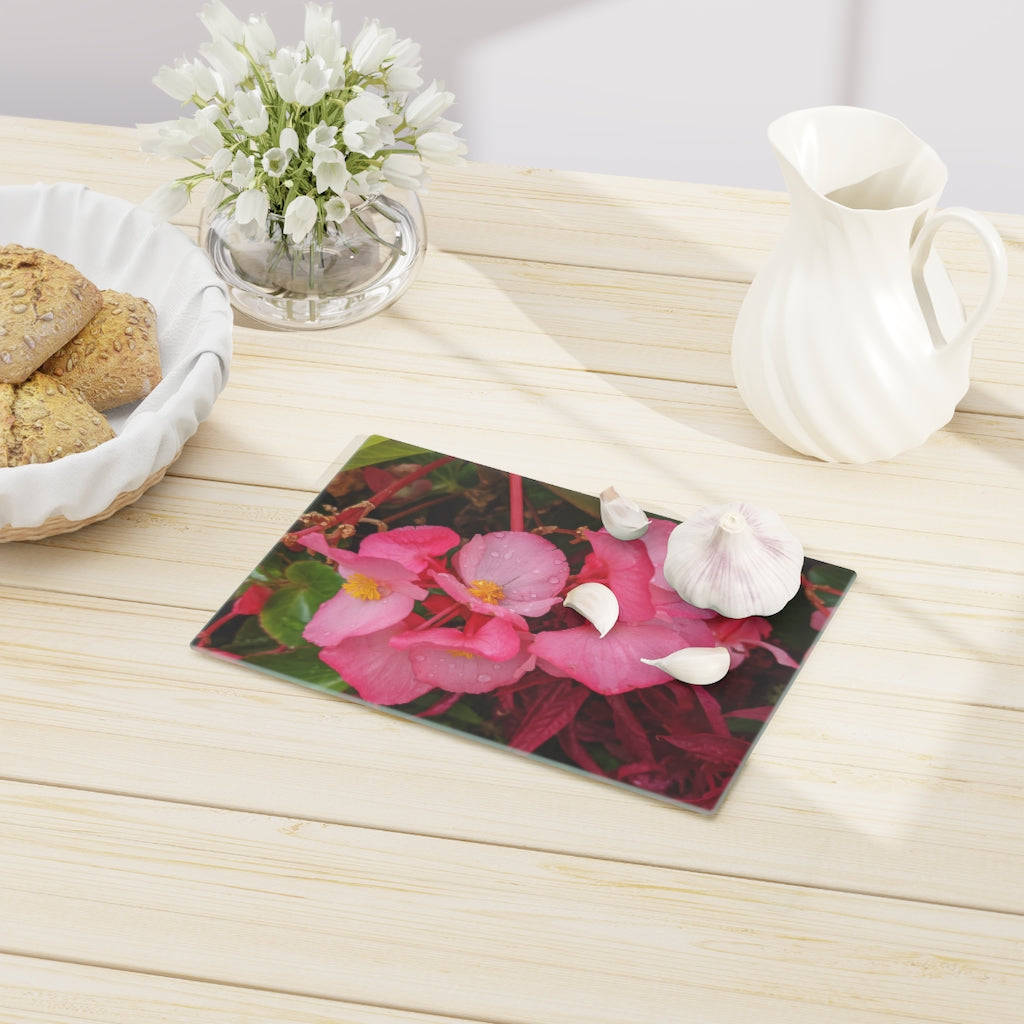 A stylish Pink Flowers Cutting Board made of tempered glass with a floral design and rubber dots for stability.