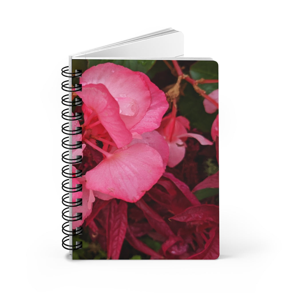 A vibrant pink flowers spiral bound journal with a glossy laminated cover, featuring lined pages for writing.