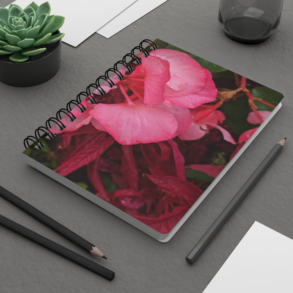 A vibrant pink flowers spiral bound journal with a glossy laminated cover, featuring lined pages for writing.