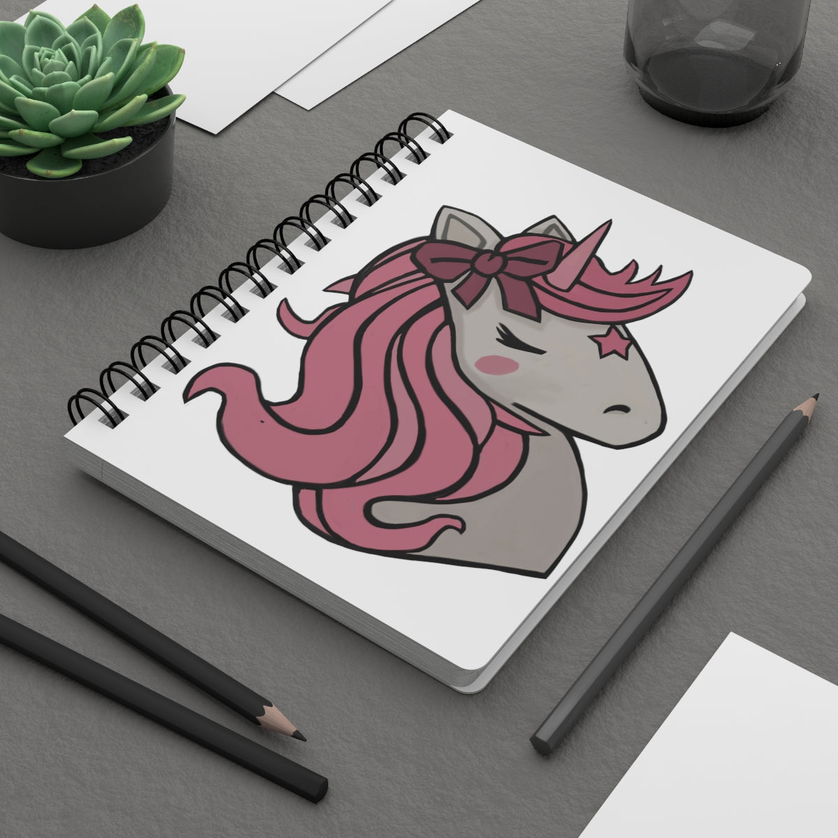 A vibrant pink hair unicorn head spiral bound journal with a glossy cover, featuring a whimsical design and lined pages inside.