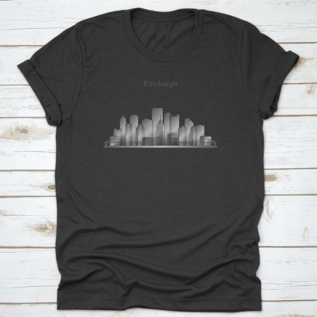 A grayscale shirt featuring the silhouette of Pittsburgh's city skyline, showcasing iconic buildings and structures.