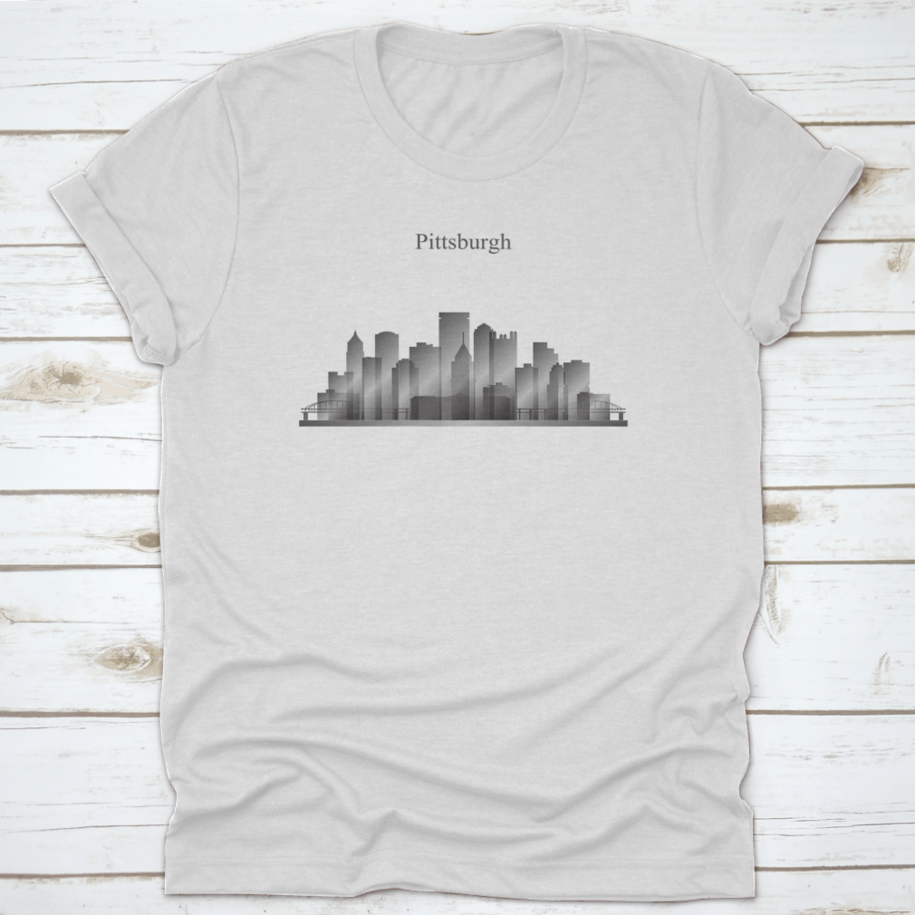 A grayscale shirt featuring the silhouette of Pittsburgh's city skyline, showcasing iconic buildings and structures.