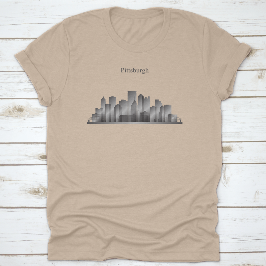 A grayscale shirt featuring the silhouette of Pittsburgh's city skyline, showcasing iconic buildings and structures.