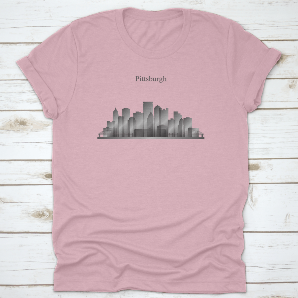 A grayscale shirt featuring the silhouette of Pittsburgh's city skyline, showcasing iconic buildings and structures.