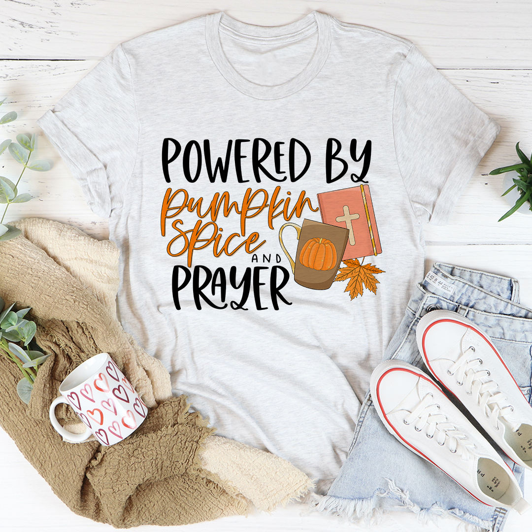 A cozy and stylish Powered By Pumpkin Spice & Prayer T-Shirt made from soft ring-spun cotton, featuring a trendy slogan.