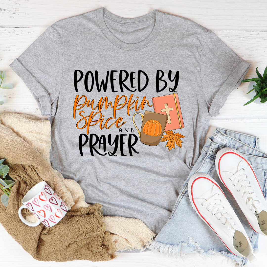 A cozy and stylish Powered By Pumpkin Spice & Prayer T-Shirt made from soft ring-spun cotton, featuring a trendy slogan.