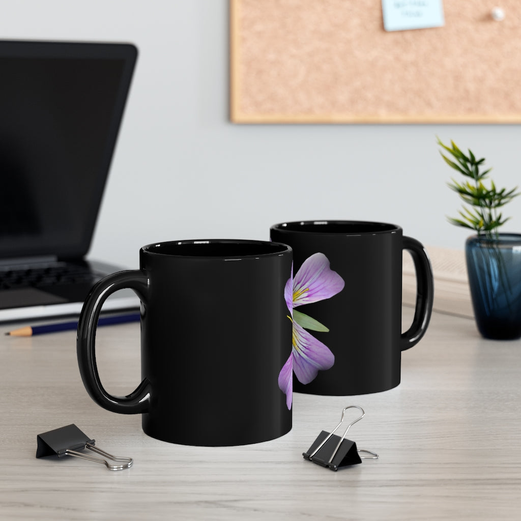 A stylish 11oz black ceramic mug featuring a vibrant purple flower design, perfect for coffee or tea.