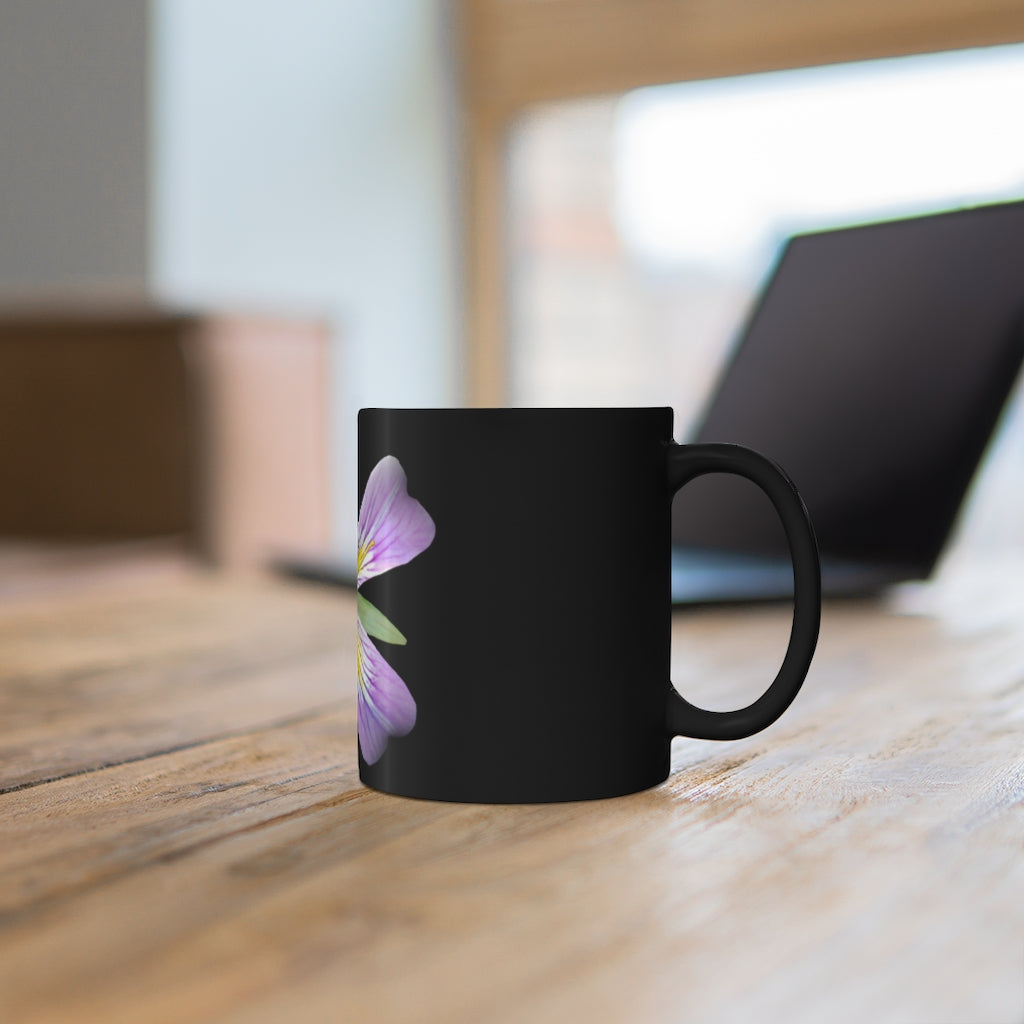 A stylish 11oz black ceramic mug featuring a vibrant purple flower design, perfect for coffee or tea.