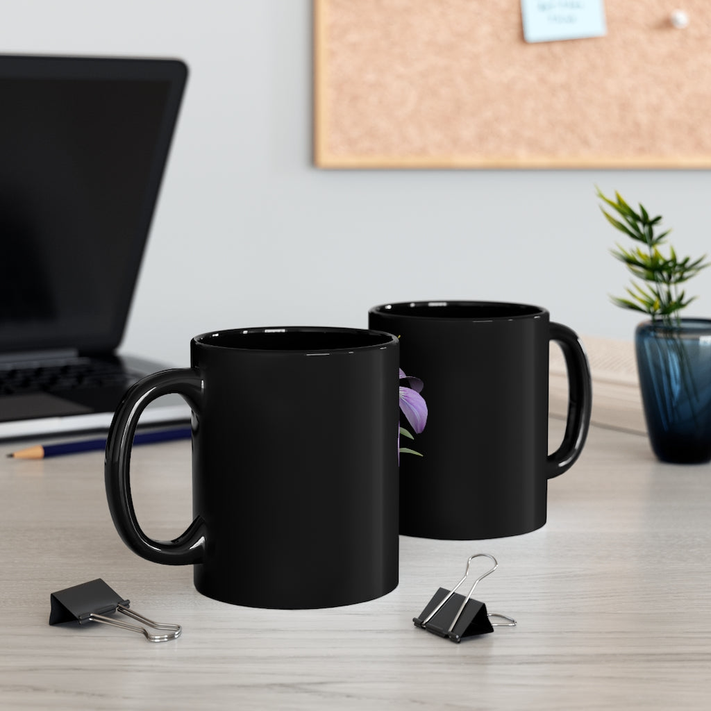 A stylish 11oz black ceramic mug featuring a vibrant purple flower design, perfect for coffee or tea.