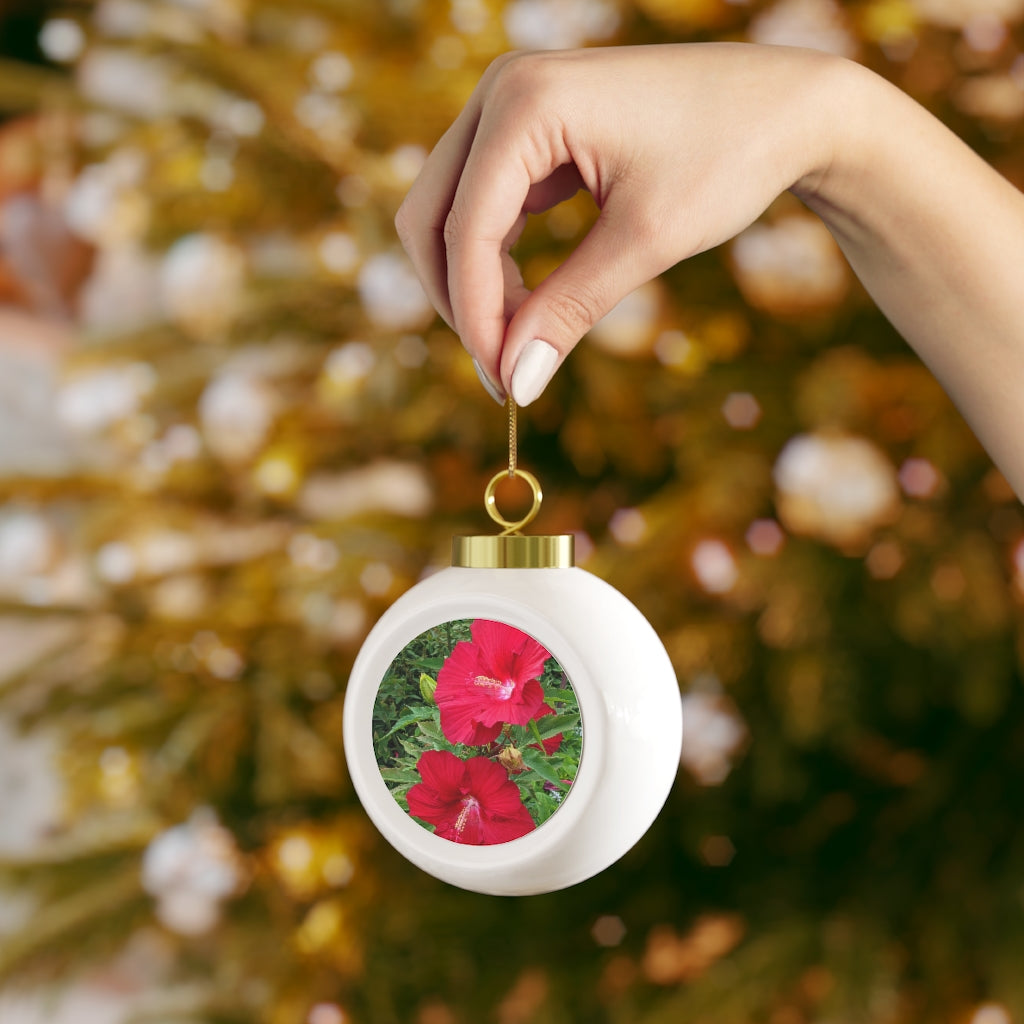 A vibrant red Christmas ball ornament featuring floral designs, glossy finish, and a gold ribbon for hanging, perfect for holiday decor.