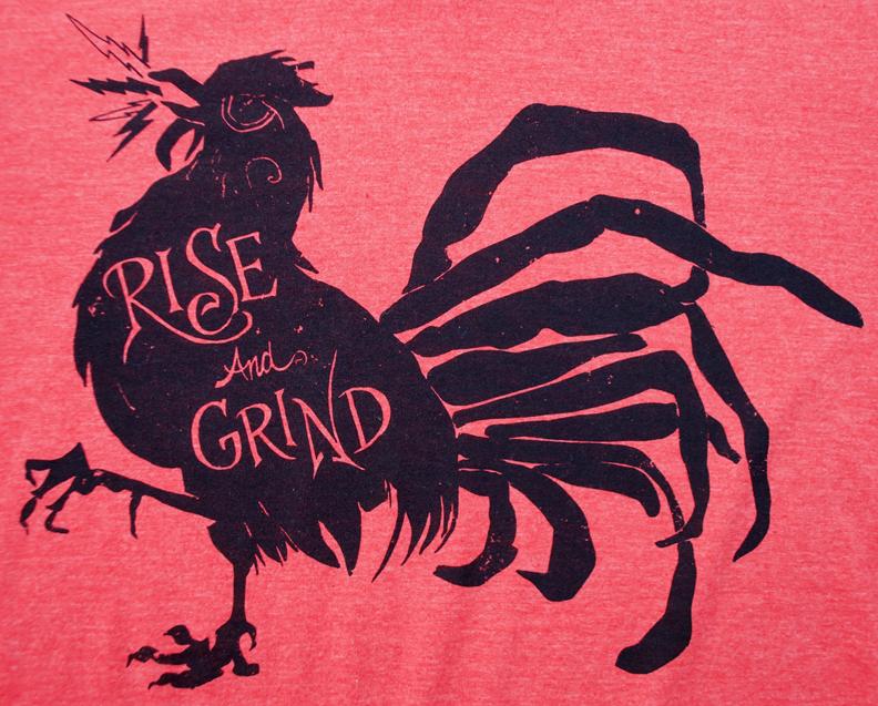 Rise and Grind Heather Red T-shirt displayed on a wooden surface, showcasing its soft fabric and vibrant color.