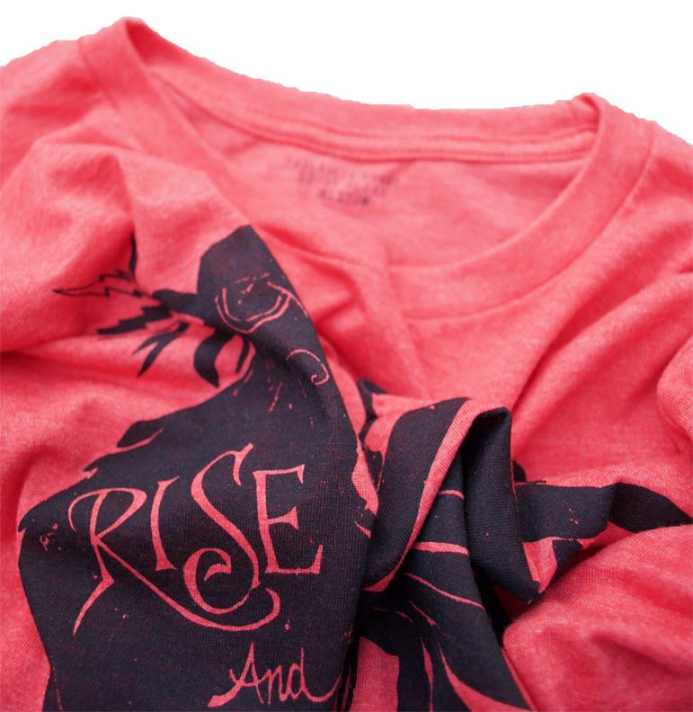 Rise and Grind Heather Red T-shirt displayed on a wooden surface, showcasing its soft fabric and vibrant color.