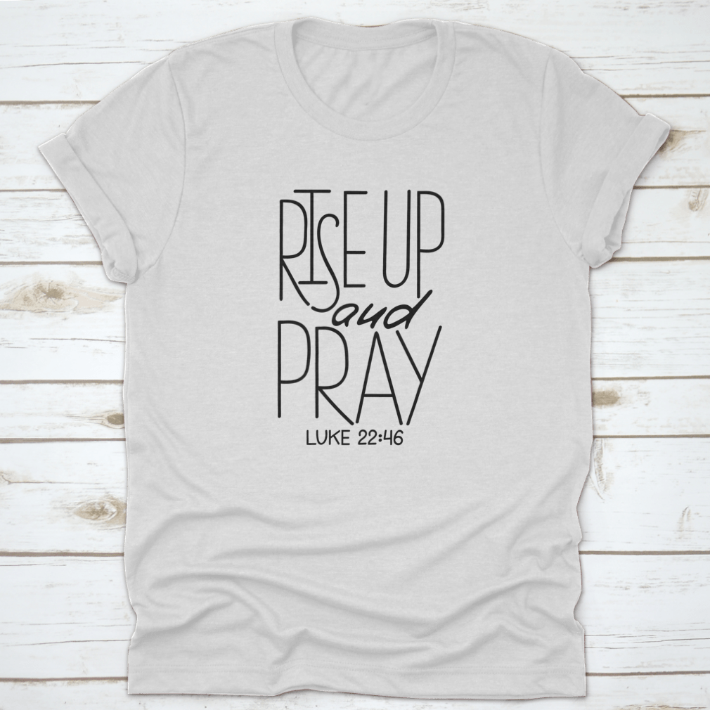 Rise Up And Pray T-Shirt featuring an inspirational quote design, made from soft cotton fabric, displayed on a neutral background.