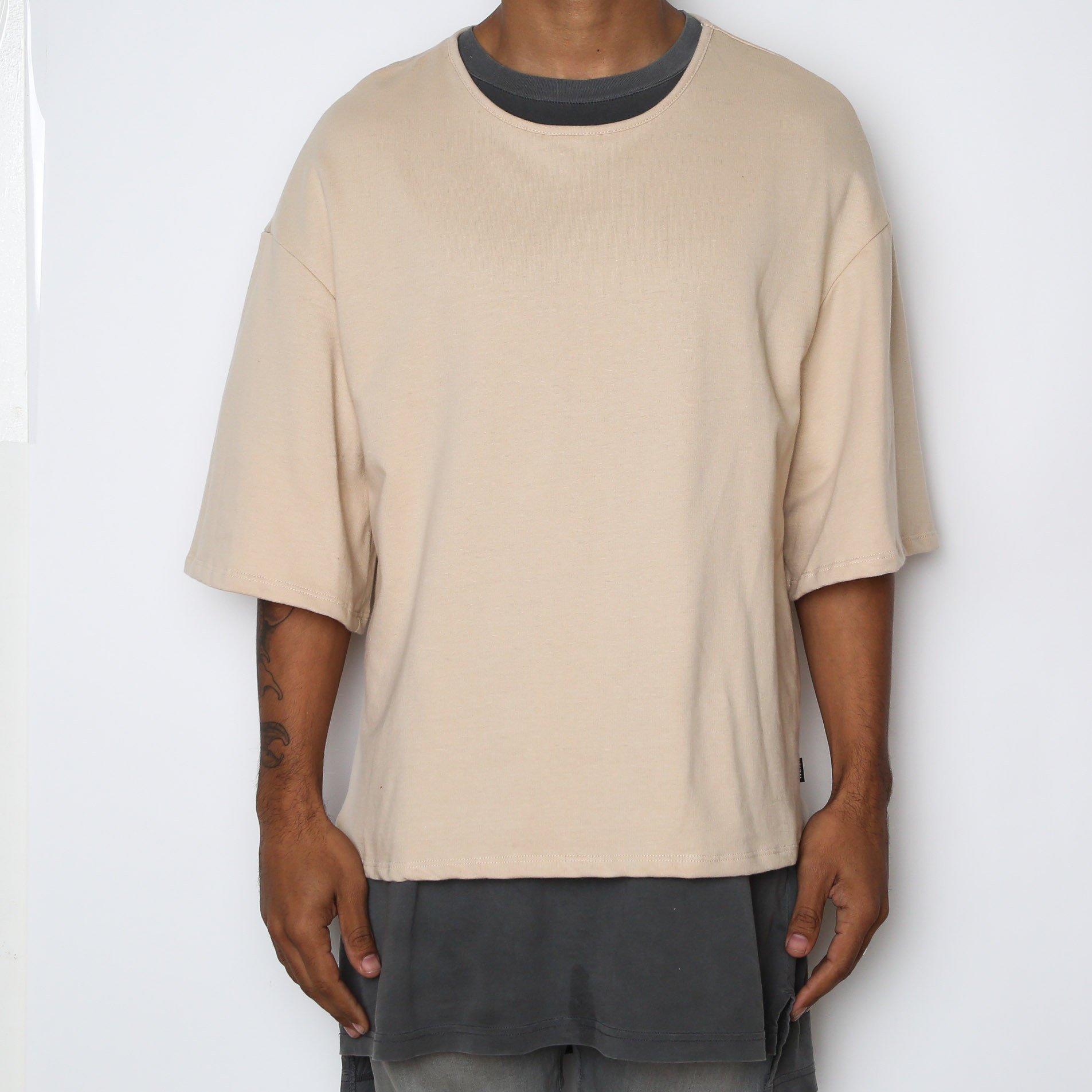 A stylish Sand Slouch Tee in a soft sand color, featuring slightly oversized sleeves and a straight hem, perfect for layering.