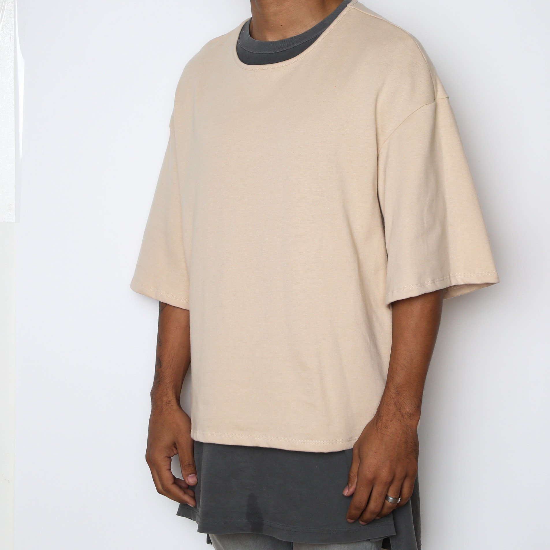 A stylish Sand Slouch Tee in a soft sand color, featuring slightly oversized sleeves and a straight hem, perfect for layering.