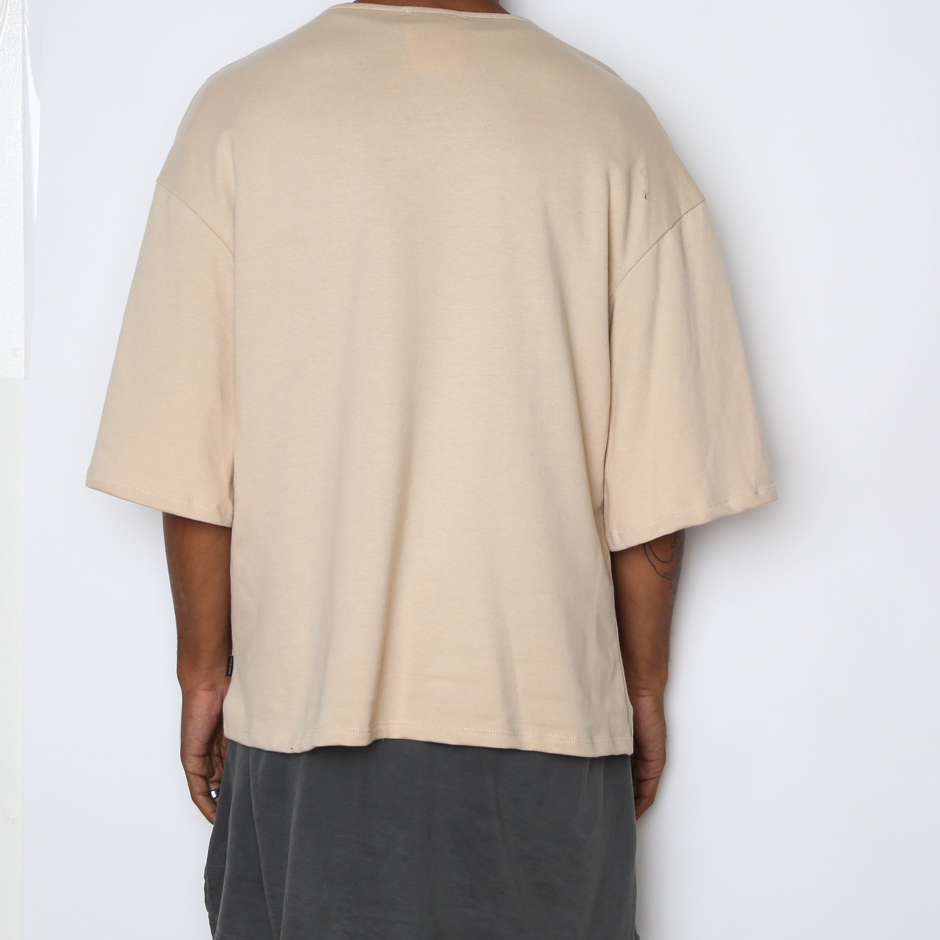 A stylish Sand Slouch Tee in a soft sand color, featuring slightly oversized sleeves and a straight hem, perfect for layering.