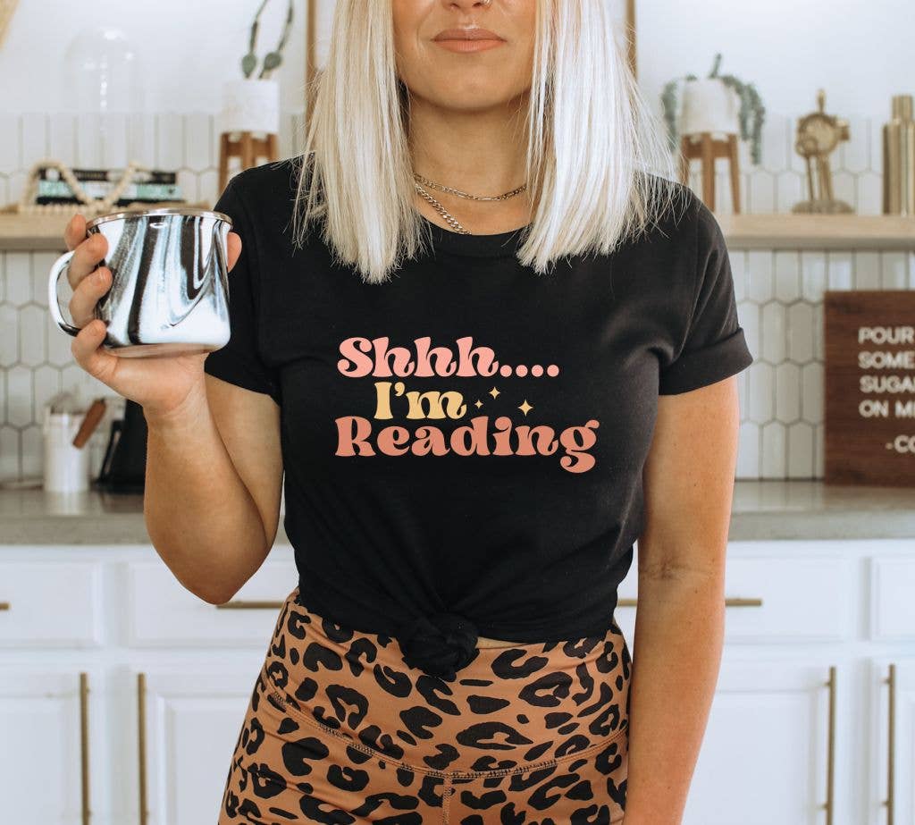 A soft, premium quality T-shirt featuring the phrase 'Shhh.. I’m Reading' in stylish print, perfect for book lovers.