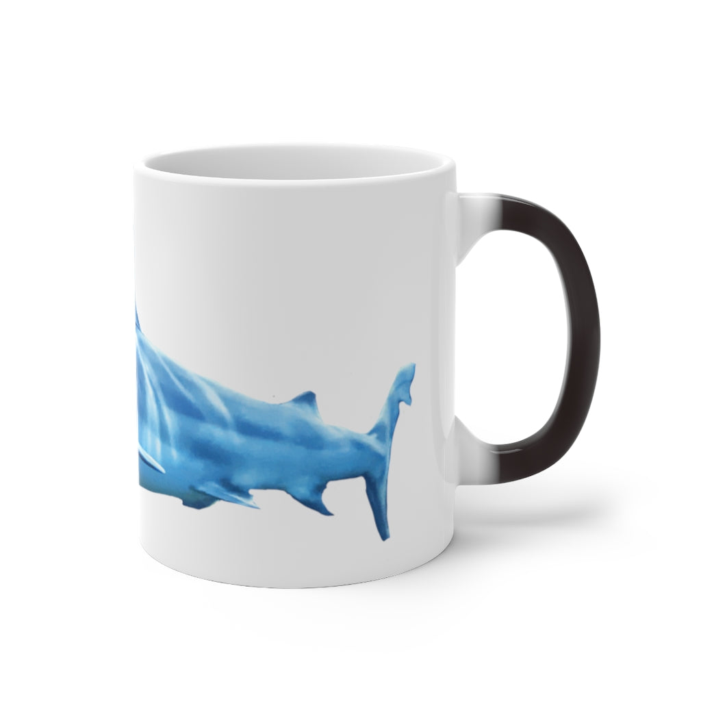 A white ceramic mug featuring a shark design that changes color when filled with hot liquid, showcasing its playful and magical feature.