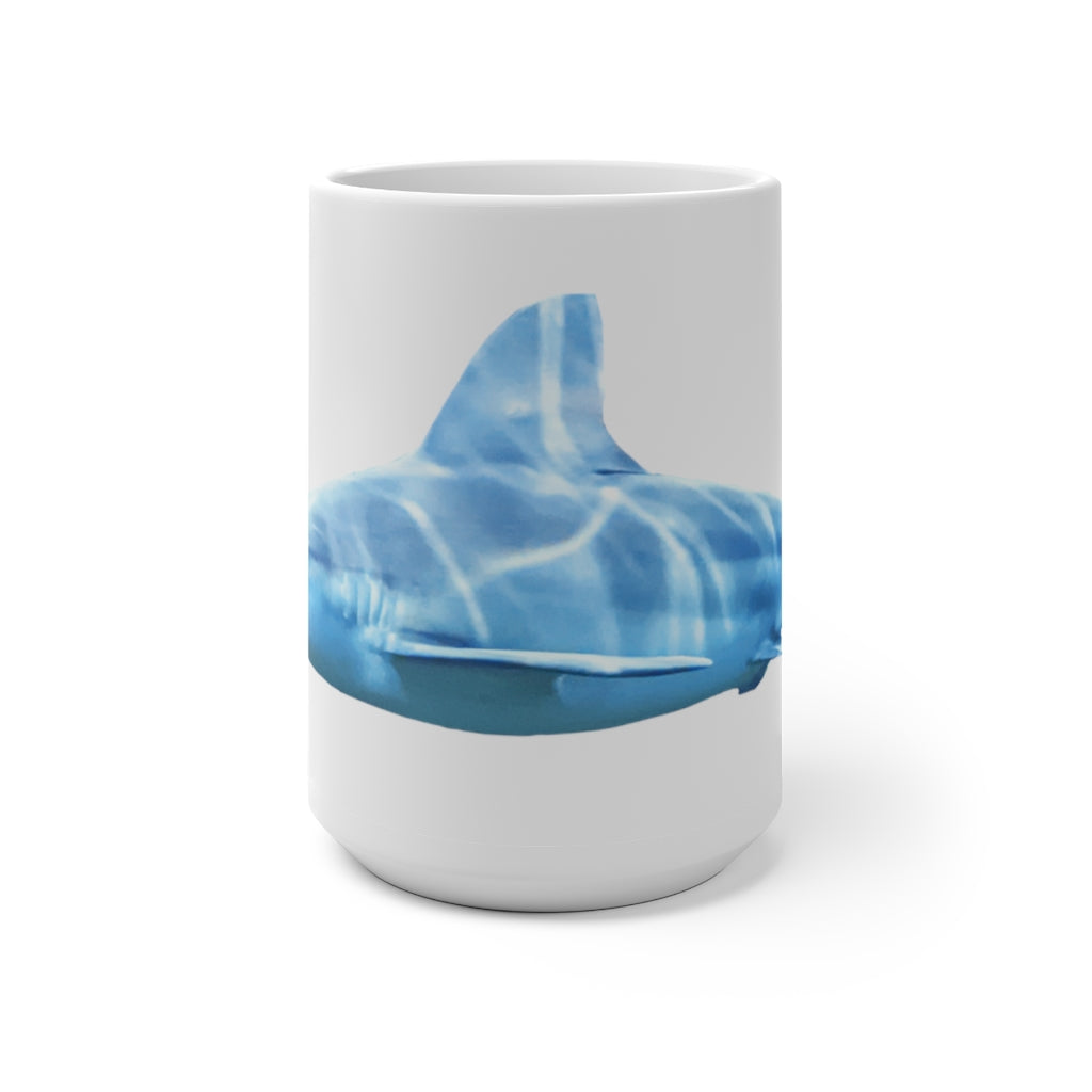 A white ceramic mug featuring a shark design that changes color when filled with hot liquid, showcasing its playful and magical feature.