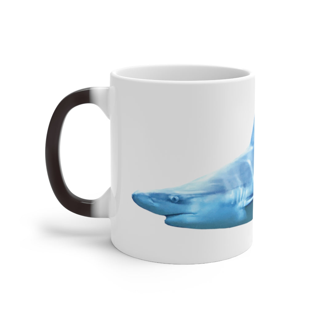 A white ceramic mug featuring a shark design that changes color when filled with hot liquid, showcasing its playful and magical feature.