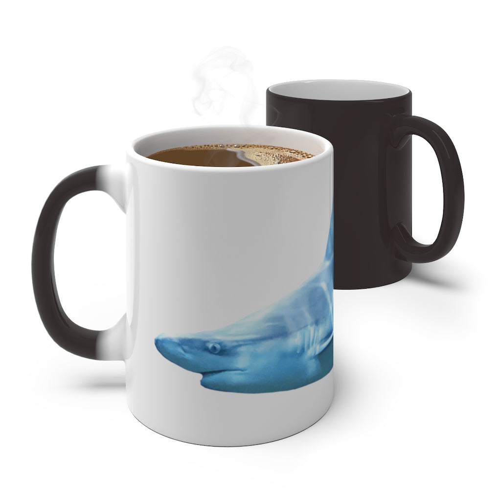 A white ceramic mug featuring a shark design that changes color when filled with hot liquid, showcasing its playful and magical feature.