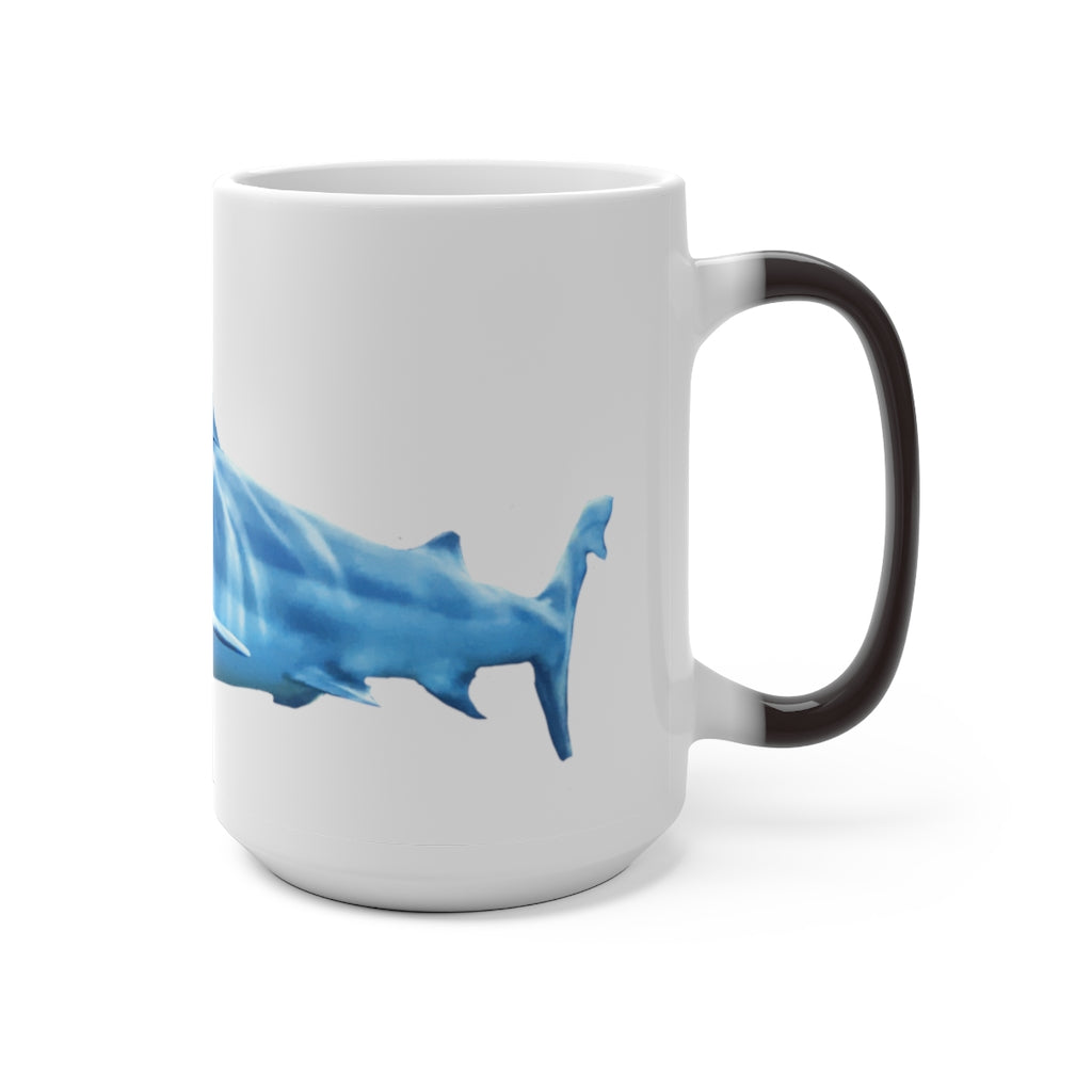 A white ceramic mug featuring a shark design that changes color when filled with hot liquid, showcasing its playful and magical feature.