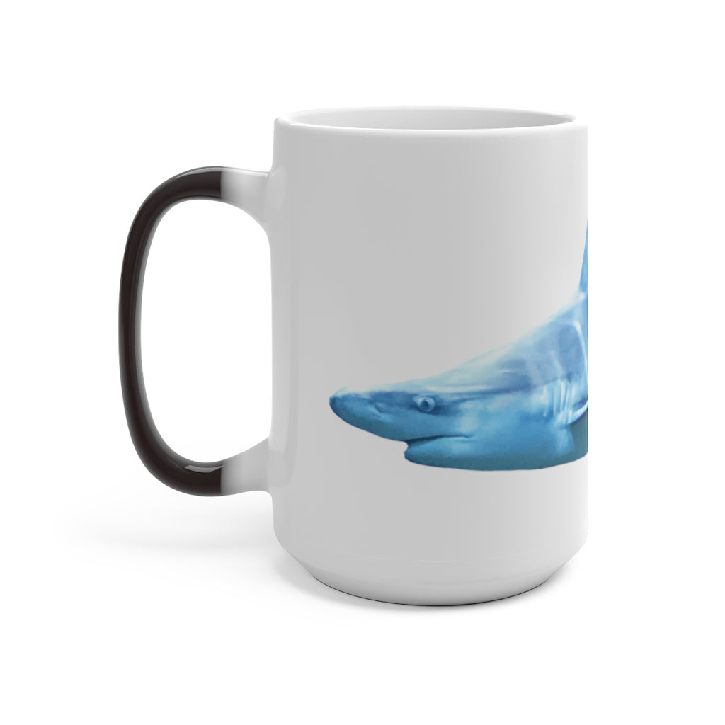 A white ceramic mug featuring a shark design that changes color when filled with hot liquid, showcasing its playful and magical feature.