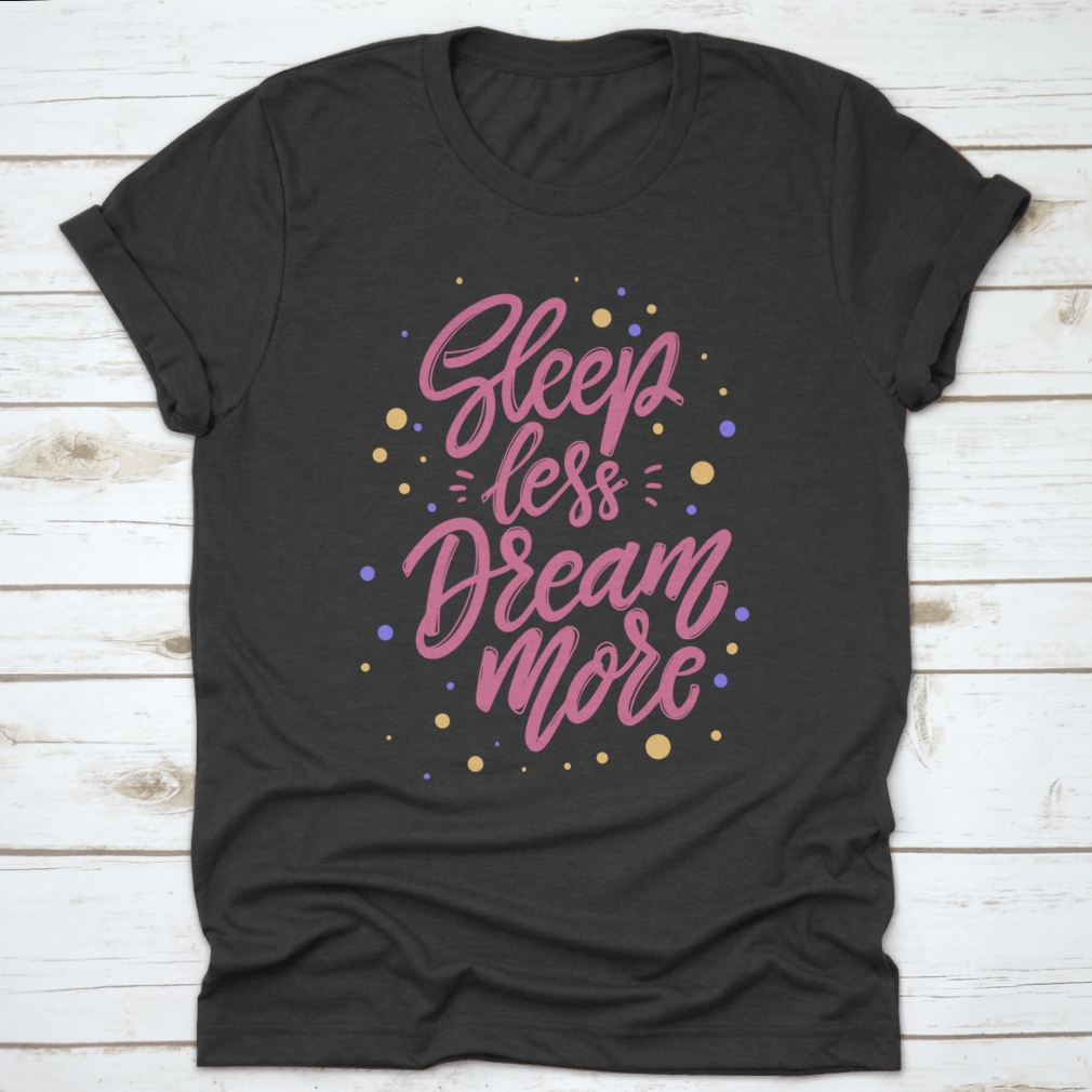 A stylish T-shirt featuring the phrase 'Sleep Less Dream More' in a cute lettering design, made from 100% cotton for comfort.